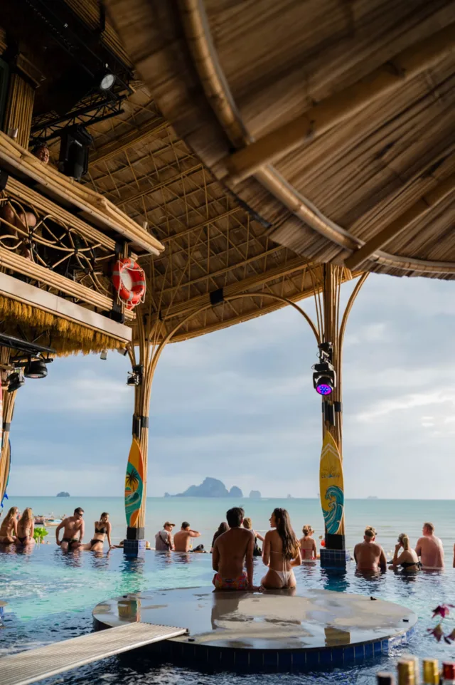 Guests in the sea-facing pool beneath Bamboo Beach Club’s thatched roof.