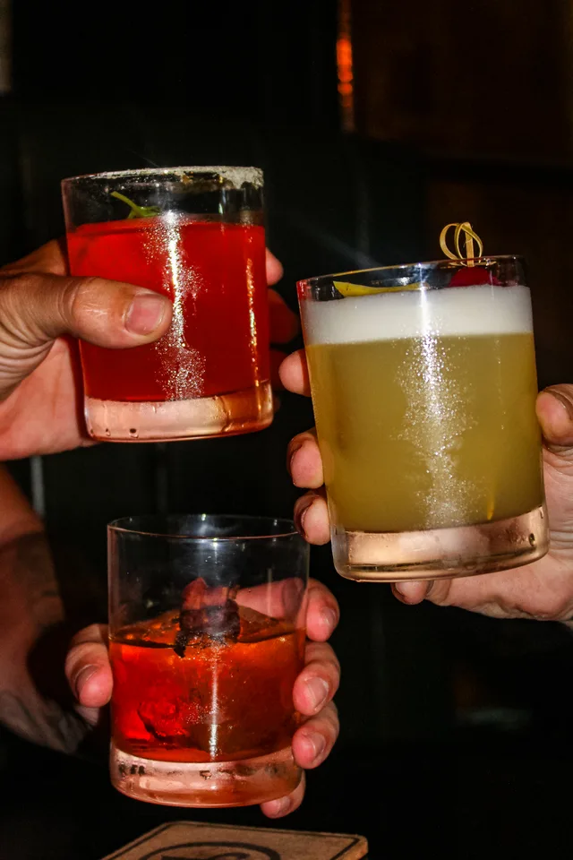 Three cocktails raised for a toast at Delaney’s Cocktail Lounge.