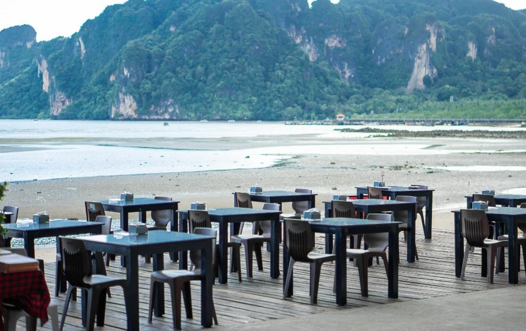 Tables on KoDam Kitchen Oceanview’s deck overlooking Ao Nam Mao’s bay and limestone cliffs.