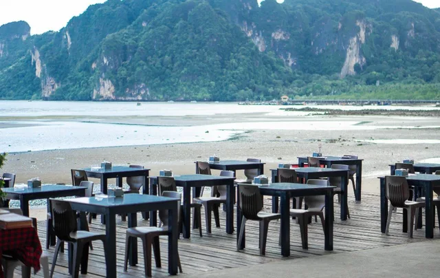 Tables on KoDam Kitchen Oceanview’s deck overlooking Ao Nam Mao’s bay and limestone cliffs.